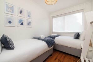 A room with two beds, a window with blinds, and wall art. - Harbour Grove Blairgowrie Coastal Sanctuary (Blairgowrie)