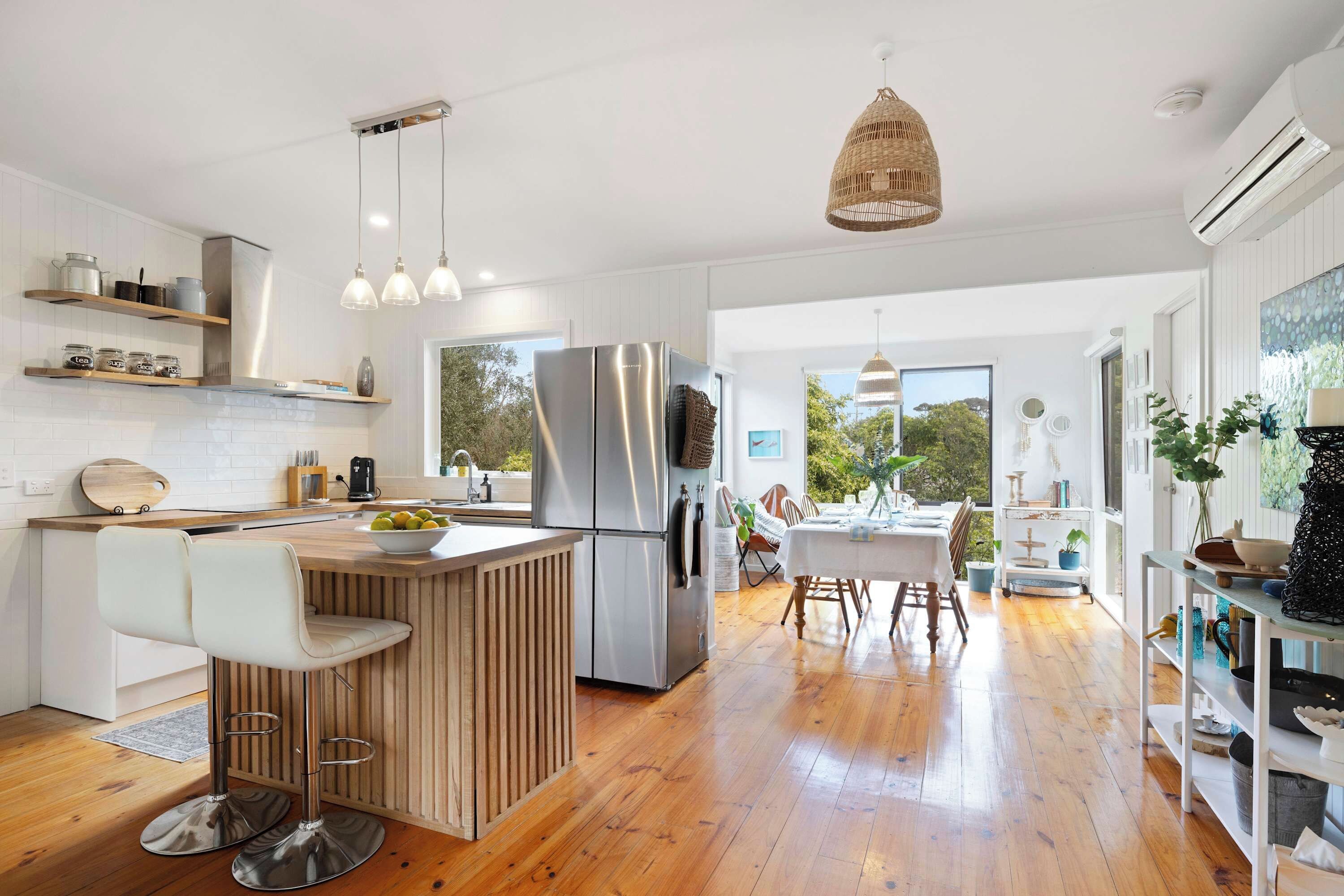 A modern kitchen with a central island, stainless steel appliances, and a dining area with a view.