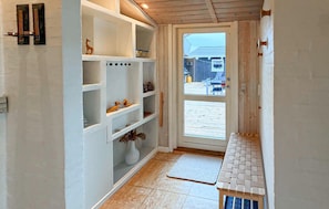 A narrow hallway with white shelving units, a door leading outside, and a small wooden bench. - Cozy home in Storvorde with house sea view (Storvorde)