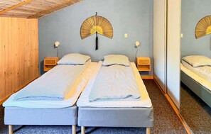 Quarto com duas camas de solteiro, cabeceiras de madeira, mesas de cabeceira e um espelho grande na parede.