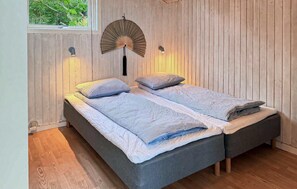 A room with two single beds, a window with a view of greenery, and a wall-mounted fan. - Cozy home in Storvorde with house sea view (Storvorde)