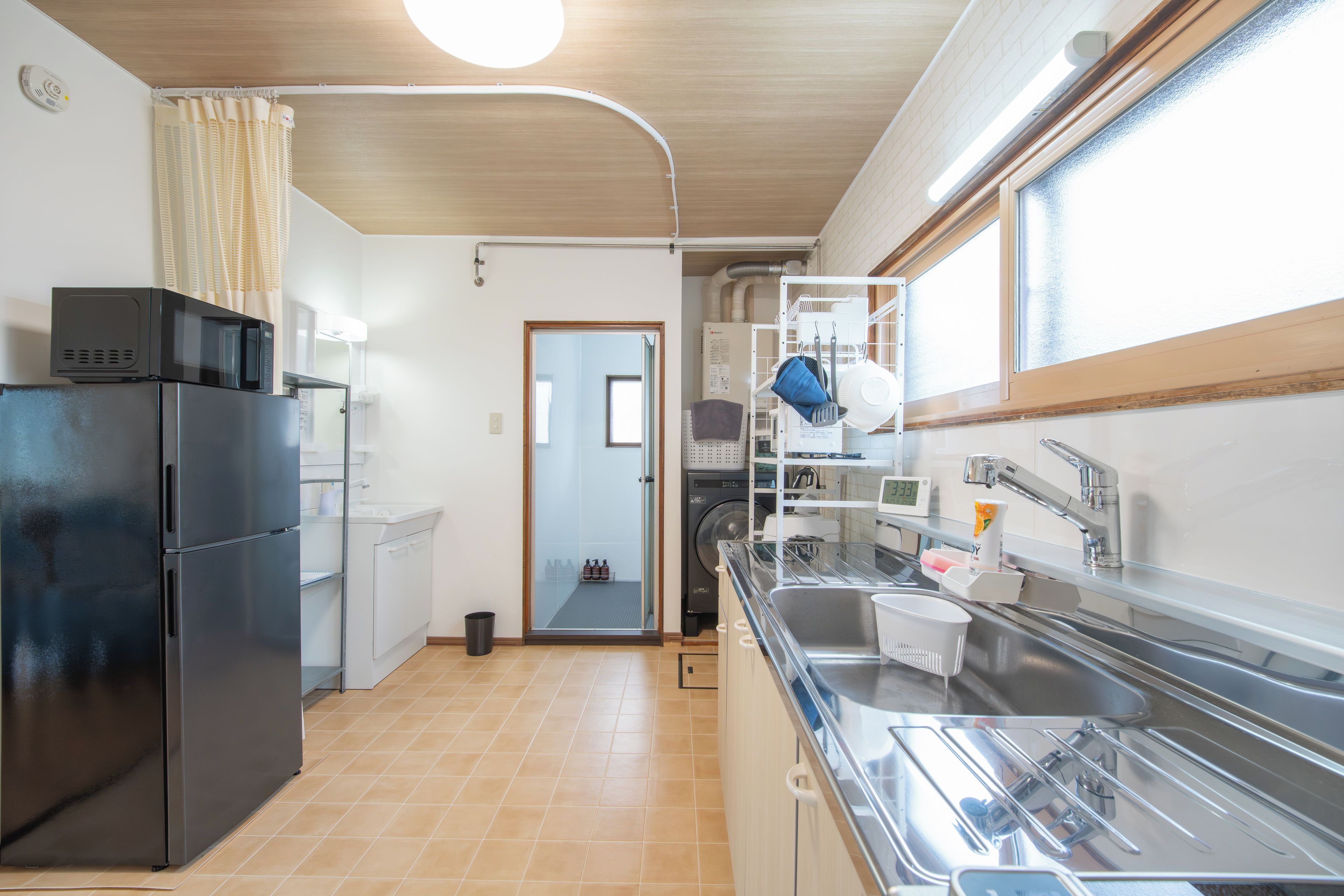 A compact kitchen with a refrigerator, microwave, sink, and a window.