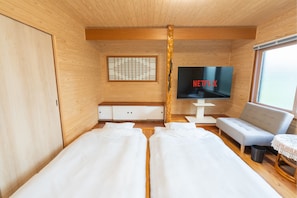 Una habitación con interior de madera, un televisor mostrando Netflix, un sofá y dos camas.