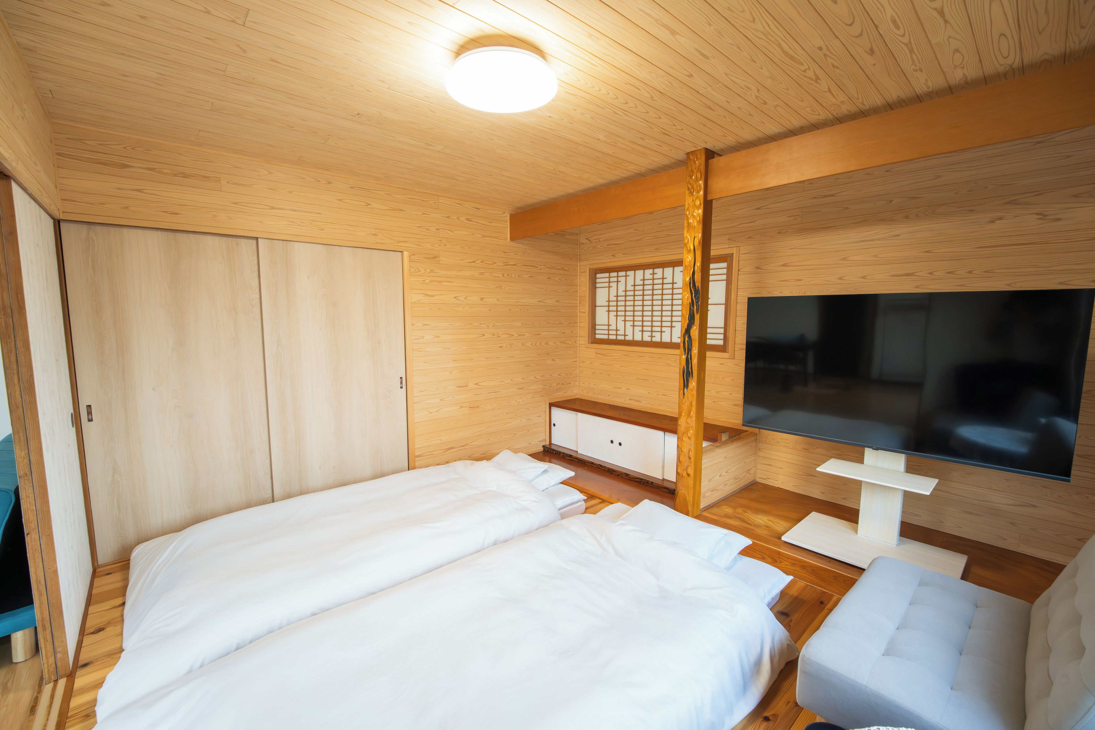 Una habitación con piso de madera, una cama, un televisor y un armario.