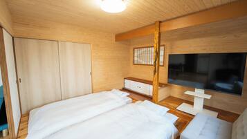 Una habitación con piso de madera, una cama, un televisor y un armario.