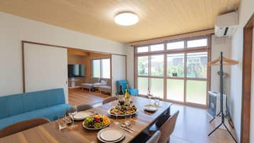 A dining area with a wooden table set for a meal, a blue sofa, and a large window with a view of greenery.