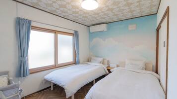 A room with two beds, a window with curtains, a wall-mounted air conditioner, and a ceiling with a floral pattern.