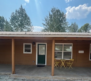A wooden building with a green door, numbered 16, and a sign indicating parallel parking.