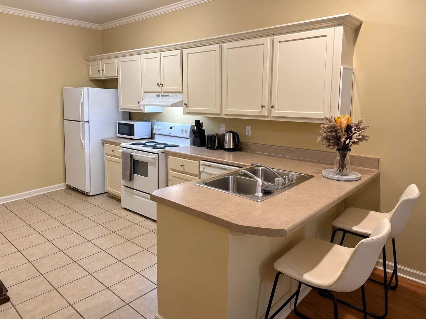 A kitchen with a central island, a refrigerator, a microwave, an oven, and a sink.