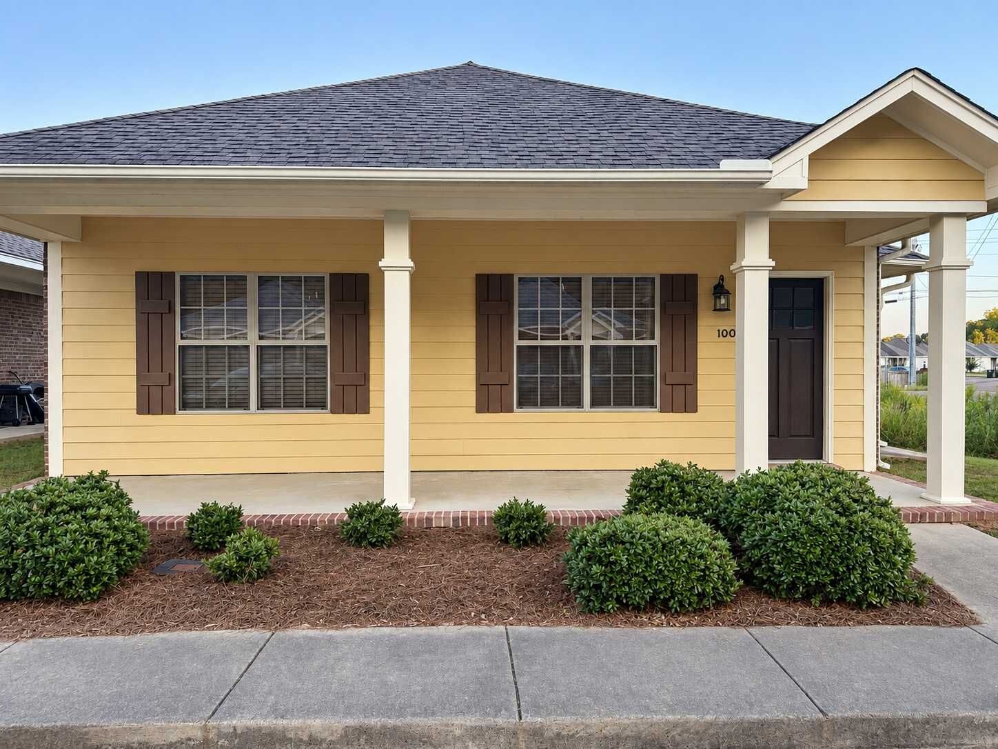 A single-story house with a gabled roof, a front porch, and a number '100' on the door.
