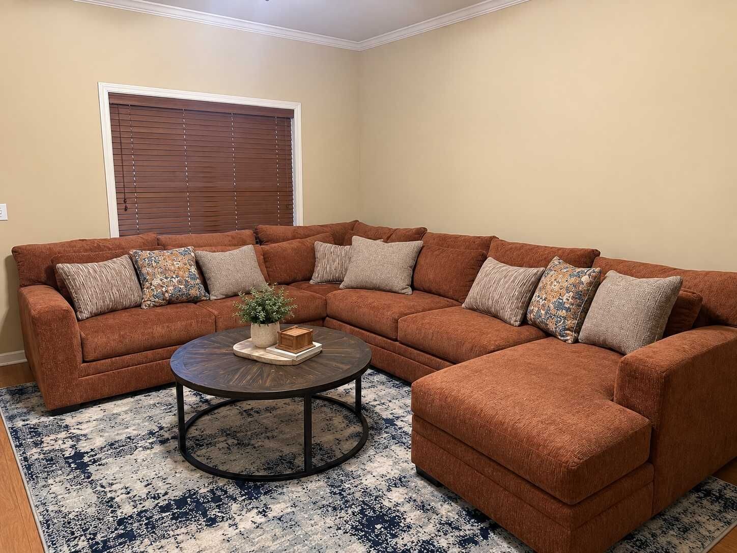 A sectional sofa with multiple cushions, a coffee table, and a patterned rug in a living room.