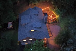 A house with a sloped roof, multiple windows, and a pathway leading to a porch area. - Charming 4-bedroom cabin in Gatlinburg!  Convenient to downtown! (Gatlinburg)