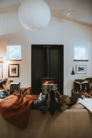 Una sala de estar acogedora con chimenea, un sofá y una persona leyendo un libro.