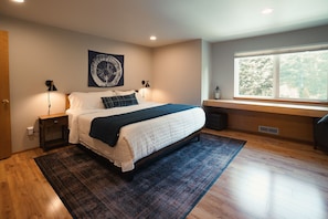 Un dormitorio con cama, lámparas de noche, una ventana y vistas a árboles.
