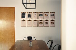 Una mesa de madera con un jarrón de flores, una pared con varias tarjetas informativas y una puerta.