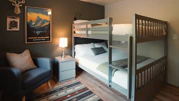 Ett rum med våningssängar, ett skrivbord, en stol, en lampa, en affisch och en matta.