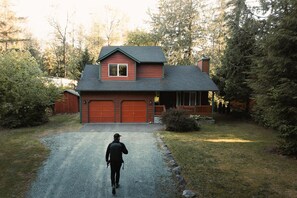 Una casa de dos pisos con fachada roja y un porche cubierto.