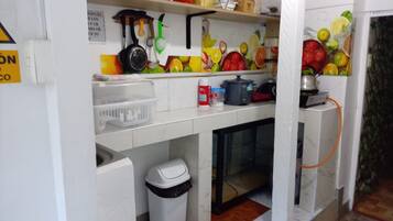 Uma cozinha com pia, lixeira, geladeira e diversos utensílios e eletrodomésticos.