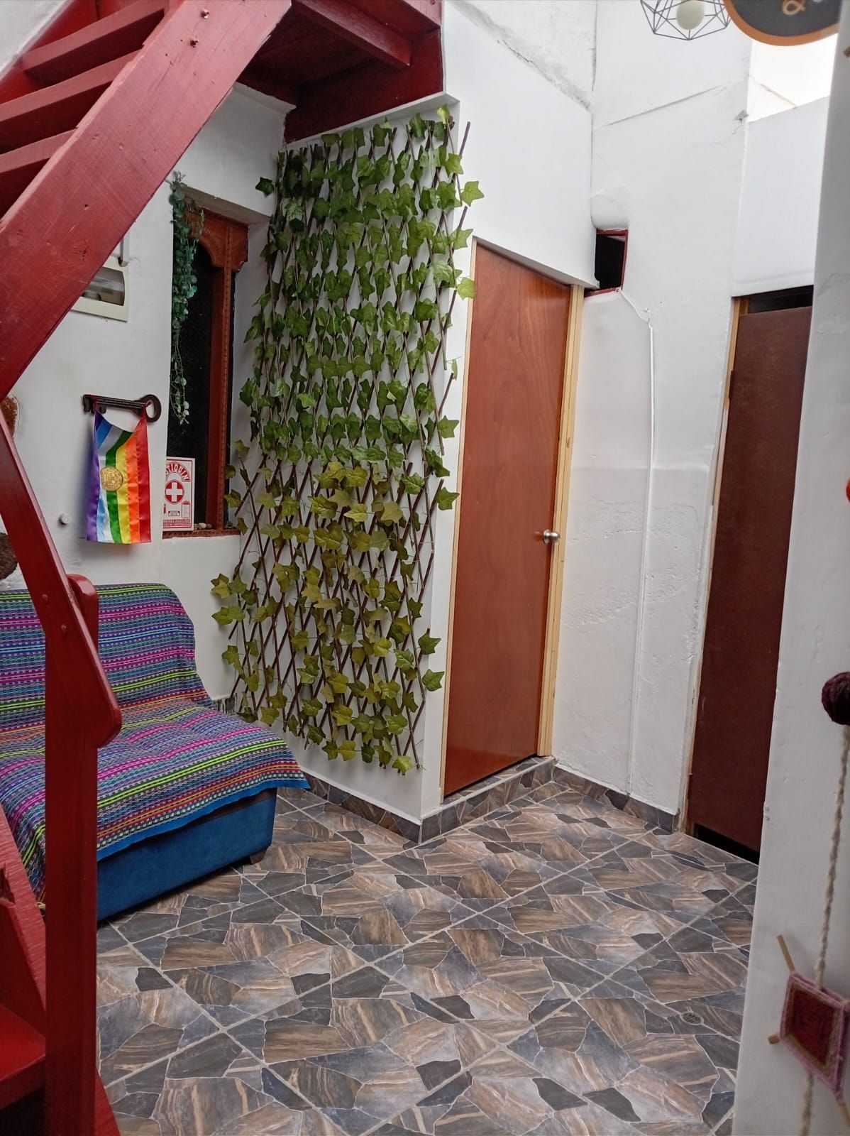 Una habitación con piso estampado, una puerta de madera y una pared con follaje verde.