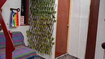 Una habitación con piso estampado, una puerta de madera y una pared con follaje verde.