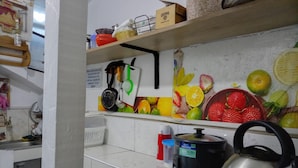 Cuina amb salabost amb rajoles, un búl, una cocedora d'arròs i diversos utensilis de cuina.