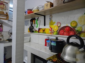 A kitchen with a tiled backsplash, a kettle, a rice cooker, and various kitchen utensils. - Casa del Valle (Cusco)