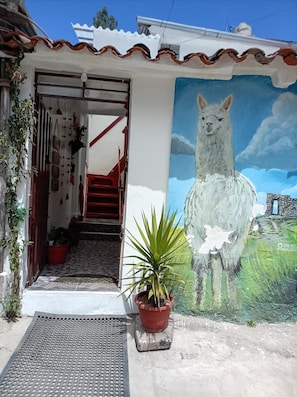 A house with a mural of a llama, a staircase, and a potted plant. - Casa del Valle (Cusco)