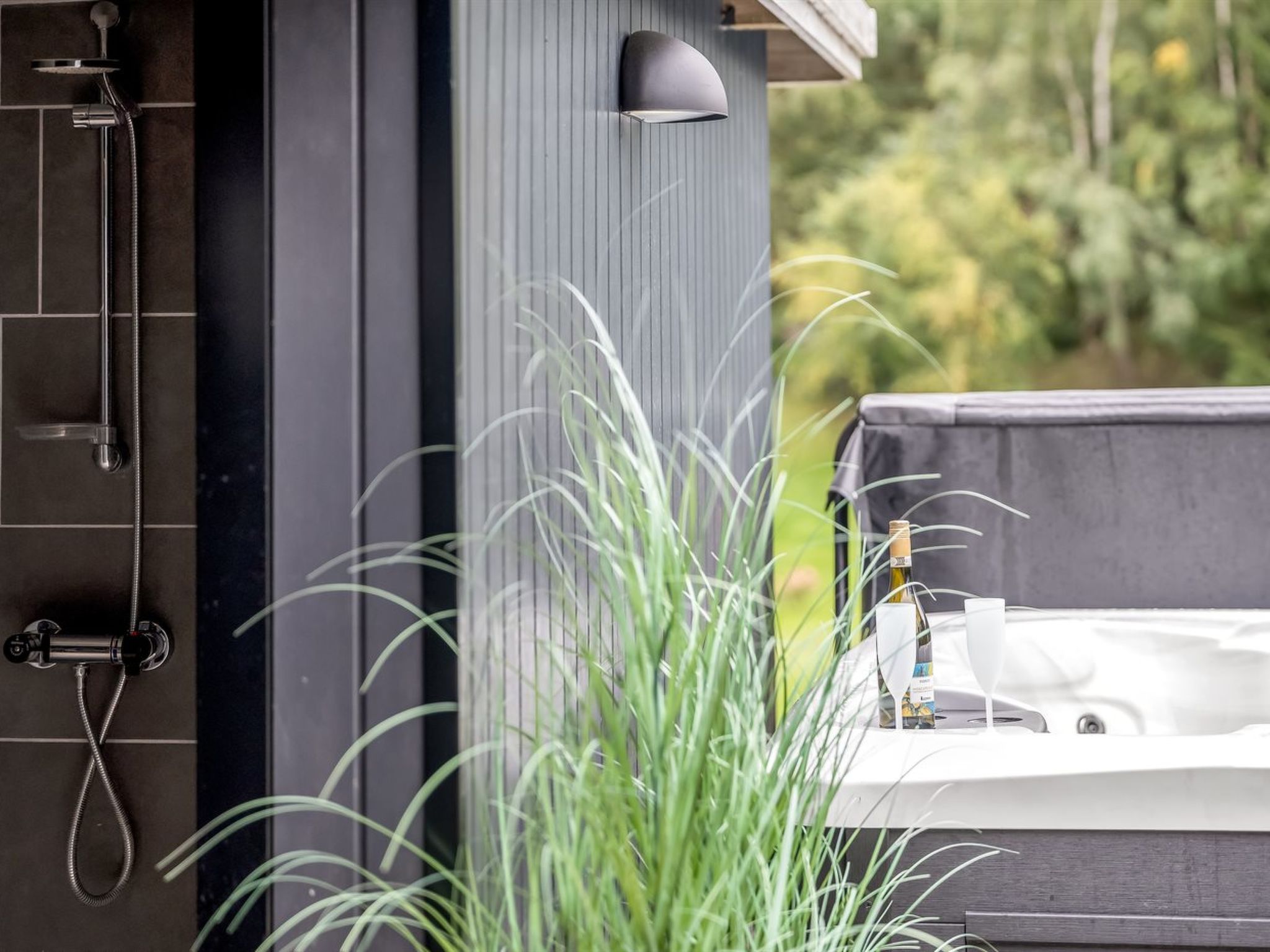 A modern bathroom with a shower, a sink, and a bottle of wine.