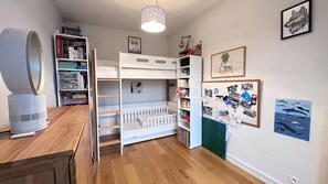Habitación infantil con literas, un escritorio, una estantería y un panel decorado con fotos.