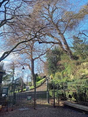 A park with a paved walkway, a metal fence, and a lamppost. - Renovated 1-Bed – Montmartre Village (18th) (Paris)