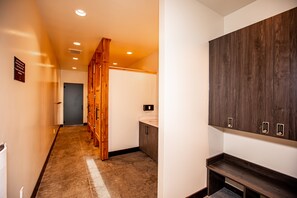 Ein Hotelgang mit Holztüren, ein Badezimmer mit Toilette und Waschbecken sowie ein Kleiderschrank mit Fernbedienung.