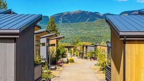 A row of modern cabins with a mountain view, a paved walkway, and a clear sky. - Top-floor corner condo l Hot Tub / Summer Pool / Gym (Whitefish)