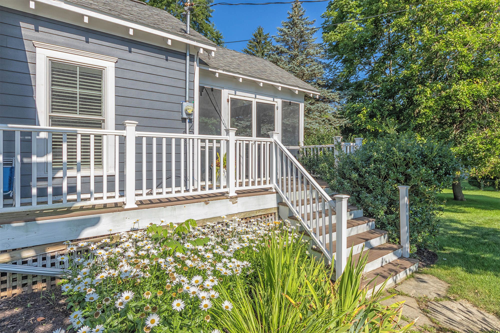 A house with a porch, a staircase, and a garden with flowers.