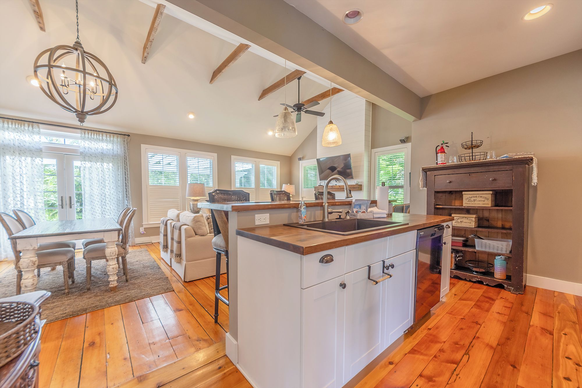 A spacious kitchen with a central island, wooden flooring, and a dining area with a table and chairs.