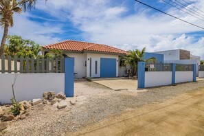 Ein Wohnhaus mit rotem Ziegeldach, weiß-blauer Fassade und einem verschlossenen Eingang.