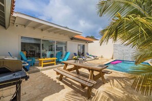 Eine Terrasse mit Pool, Gartenmöbeln und Grill.