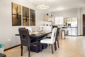 A modern kitchen with a dining area, featuring a chandelier, stainless steel appliances, and a clean, neutral color palette. - Private HotTub Escape:ModernLuxe Townhome 2BR3BA (Noord)