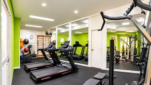 Ein Fitnessstudio mit Laufbändern, Kraftgeräten und einer Spiegelwand.
