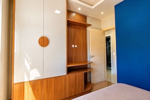 Quarto moderno com guarda-roupa, cama e parede azul de destaque.