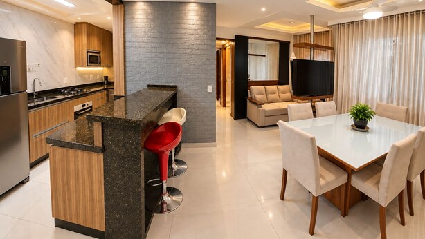 Eine moderne Küche mit Kochinsel, ein Essbereich mit Tisch und Stühlen sowie ein Wohnbereich mit Sofa und Fernseher.