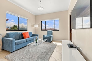 A living room with a sofa, armchair, glass coffee table, and a rug. - Private Pool Paradise: Luxe Resort Living (Noord)