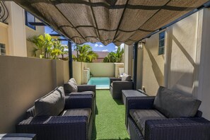 A covered outdoor seating area with wicker furniture and a pool. - Private Pool Paradise: Luxe Resort Living (Noord)