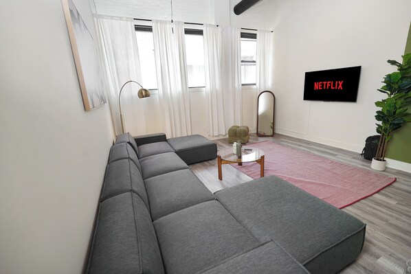 Una sala de estar moderna con un sofá modular, una mesa de centro, un televisor de pantalla plana y una planta en maceta.