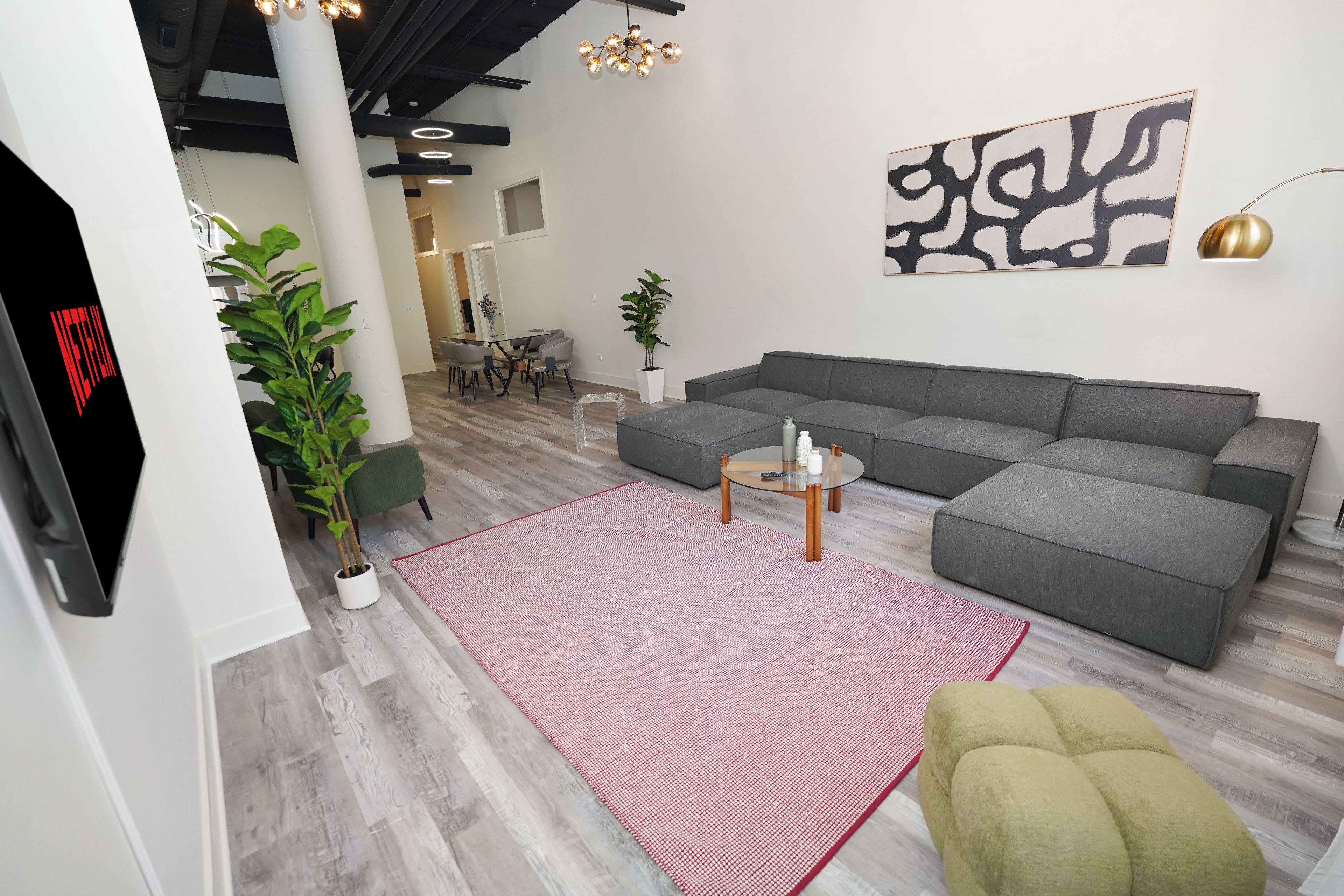 A modern living room with a sectional sofa, a glass coffee table, and a red rug.