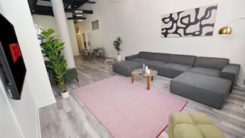 A modern living room with a sectional sofa, a glass coffee table, and a red rug.