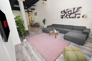Una sala moderna con un sofá seccional, una mesa de centro de vidrio y una alfombra roja.