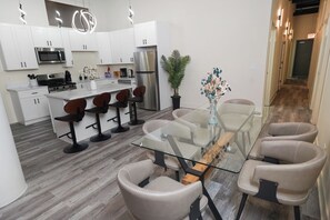 Una cocina moderna con armarios blancos, electrodomésticos de acero inoxidable y una isla central con taburetes de bar.