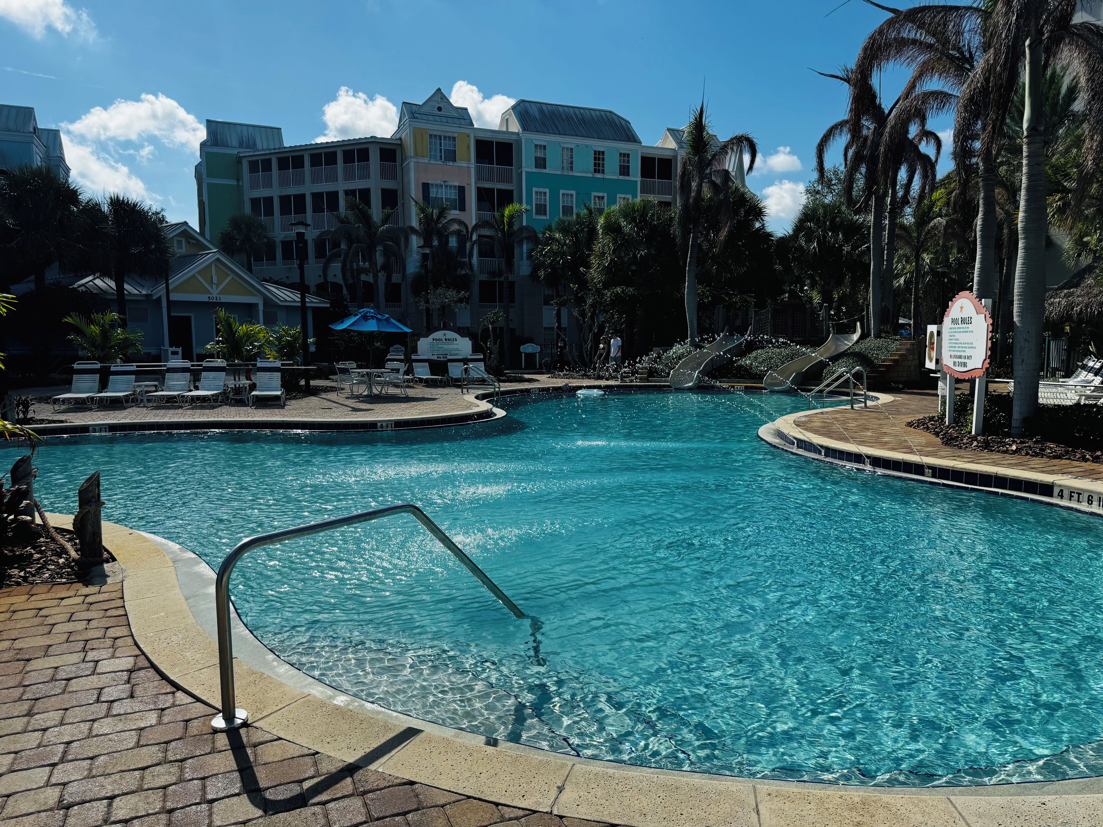A swimming pool with a poolside area, lounge chairs, and a sign indicating pool rules.