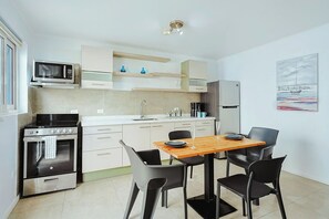 A modern kitchen with a dining area, including a stove, oven, microwave, and a table with chairs. - Charming & Private - 1BR/1BA - 3 min Palm Beach (Noord)