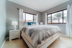 A bedroom with a bed, nightstands, and a window with curtains.